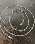 Silver  figaro chain necklace on a textured dark surface