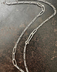 Silver  figaro chain necklace on a textured dark surface