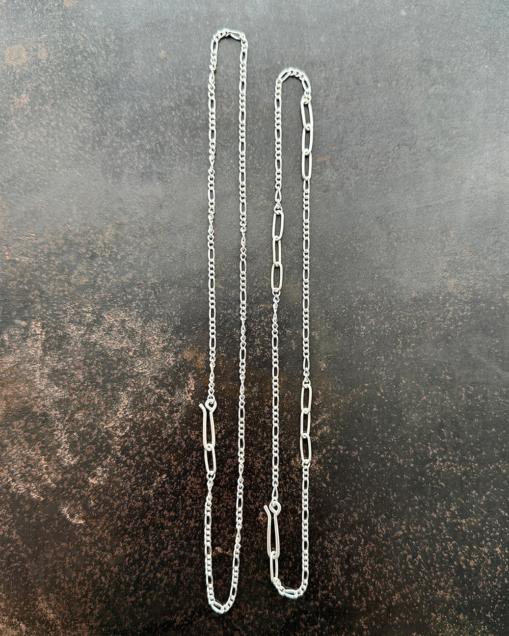 Silver  figaro chain necklace on a textured dark surface