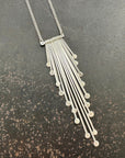 Silver fringe necklace on a dark textured surface