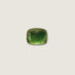 A polished green tourmaline cabochon with a cushion-cut shape, resting on a textured gray stone surface.