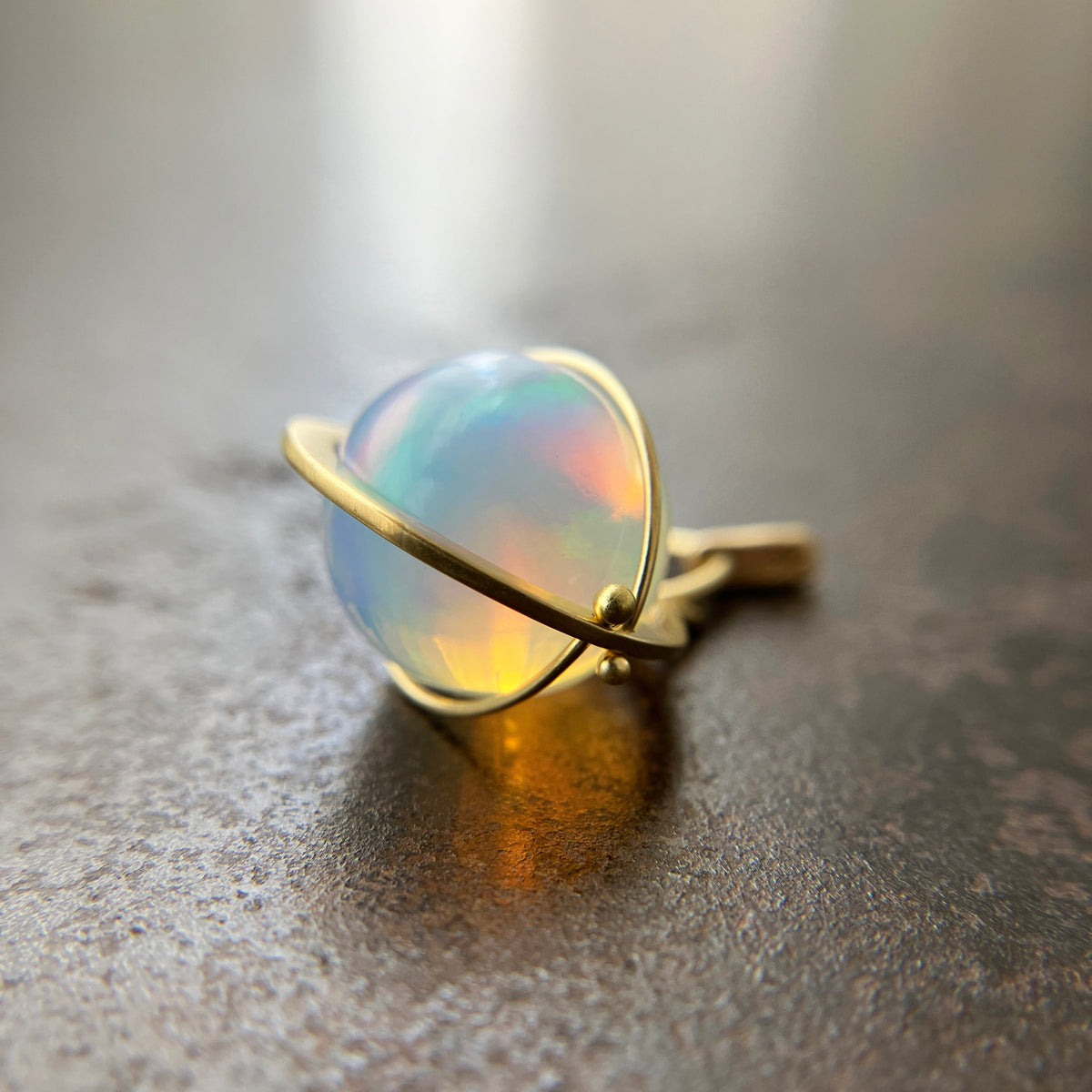An ethiopian opal orb pendant in an 18k gold setting