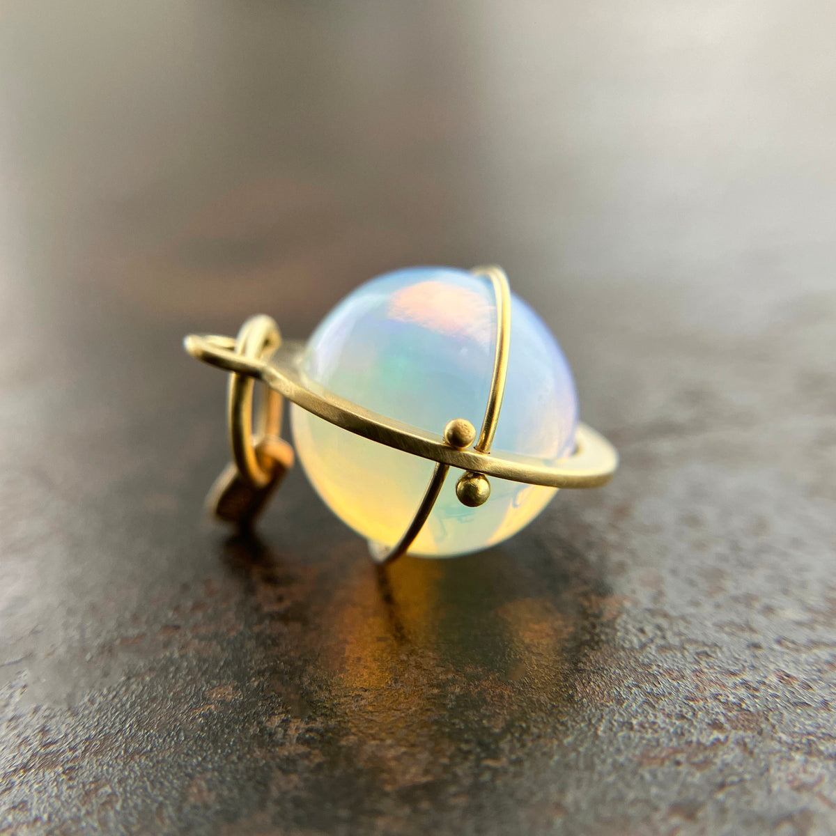 An ethiopian opal orb pendant in an 18k gold setting