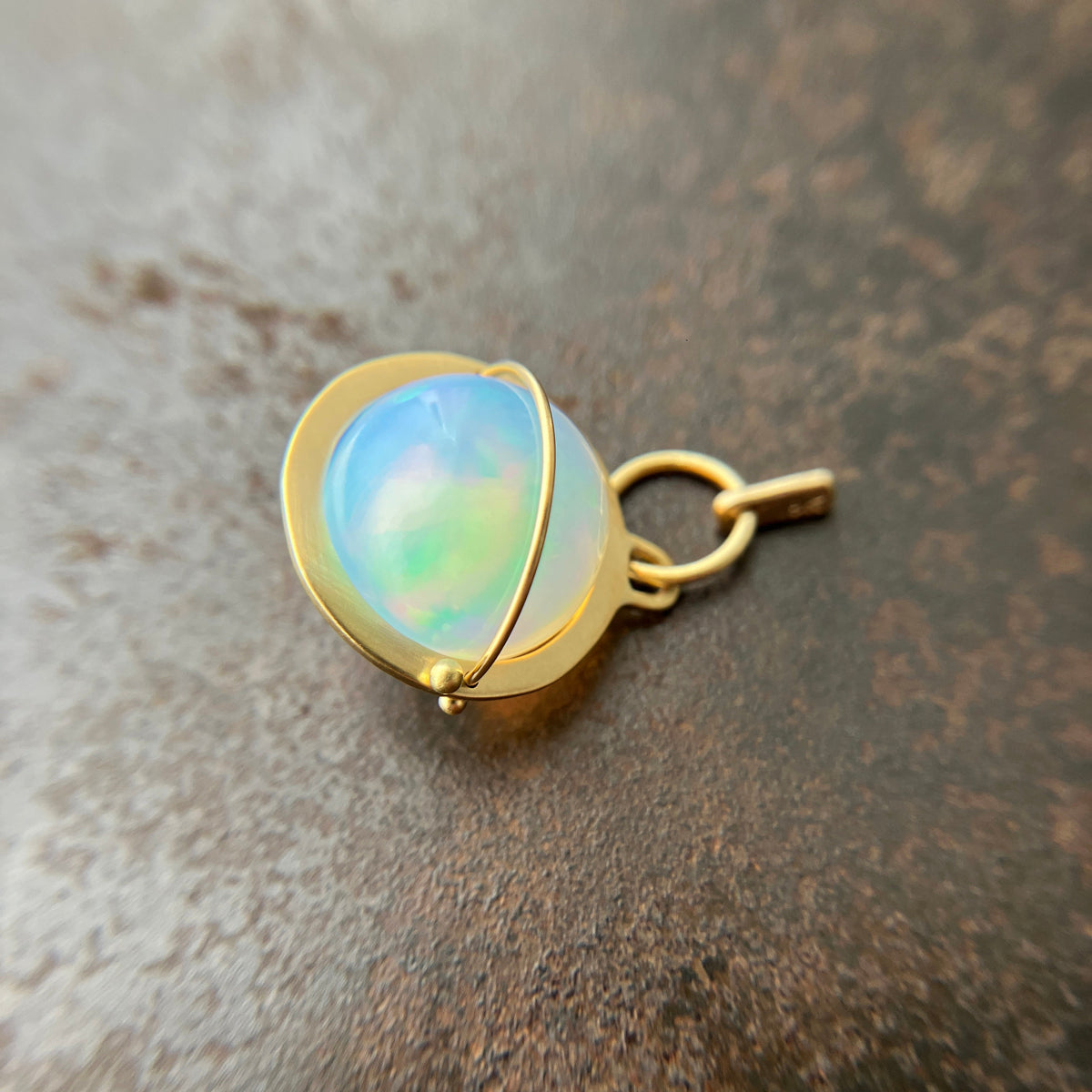 An ethiopian opal orb pendant in an 18k gold setting