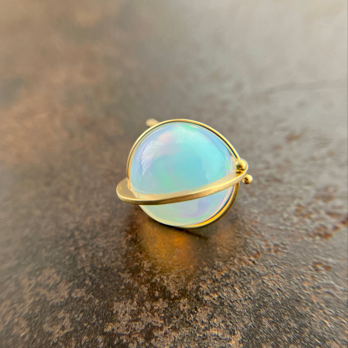 An ethiopian opal orb pendant in an 18k gold setting