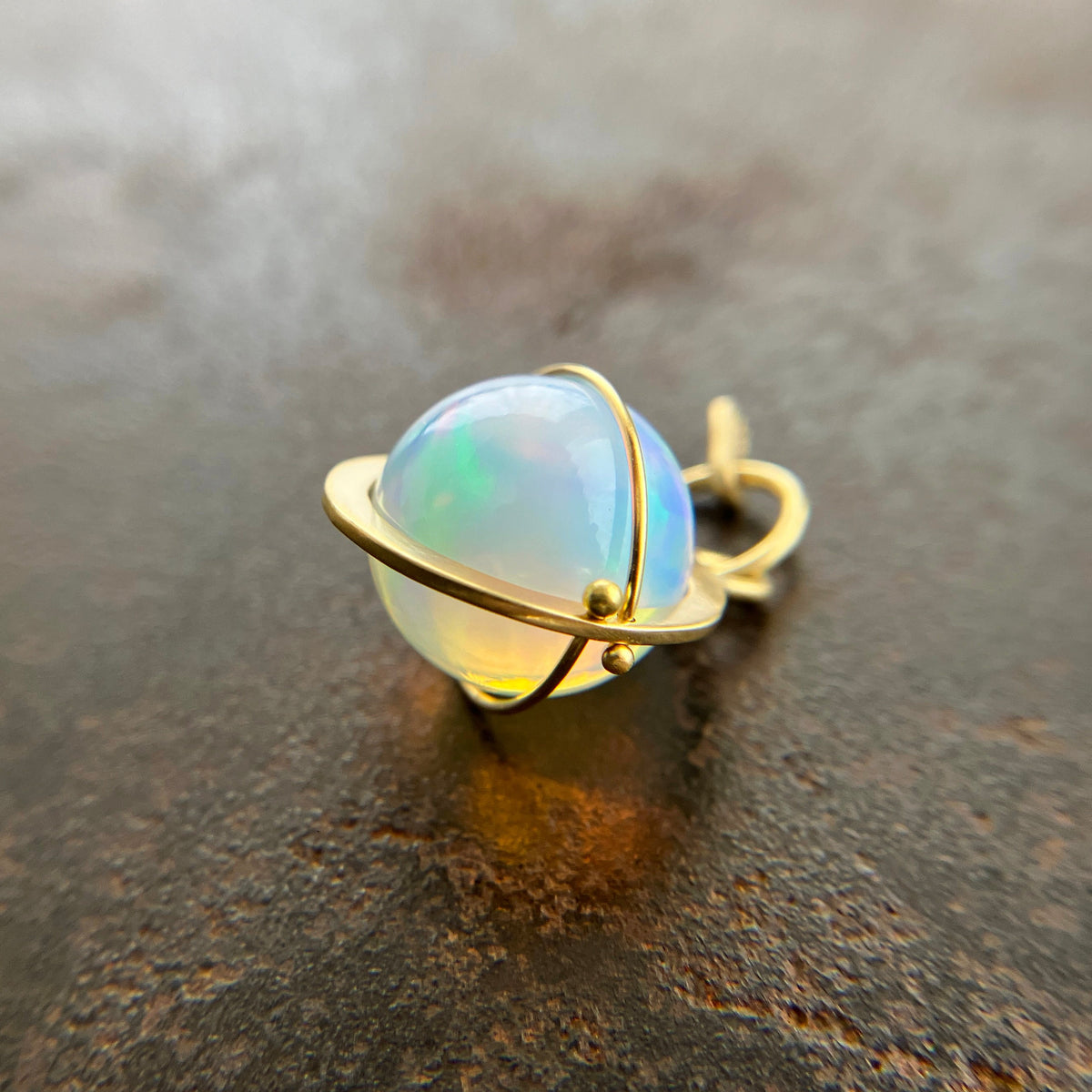 An ethiopian opal orb pendant in an 18k gold setting