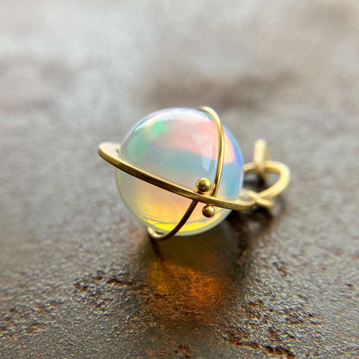 An ethiopian opal orb pendant in an 18k gold setting