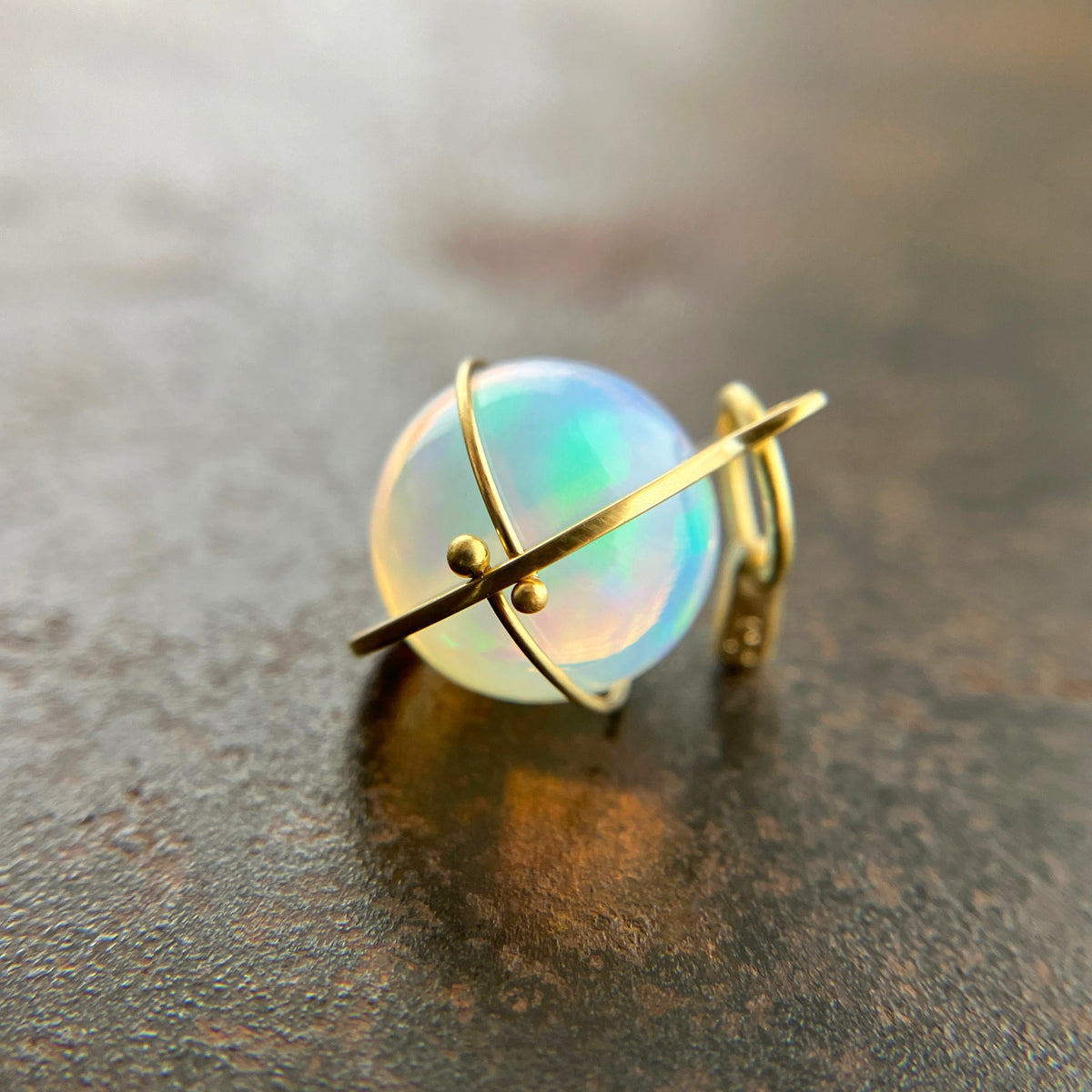 An ethiopian opal orb pendant in an 18k gold setting