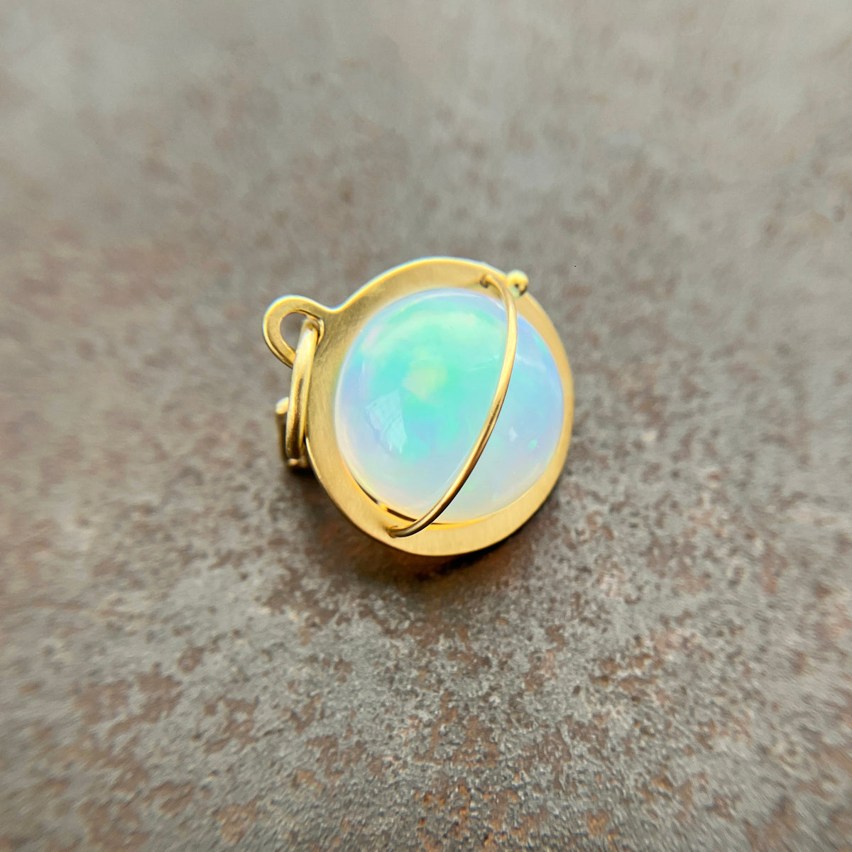 An ethiopian opal orb pendant in an 18k gold setting