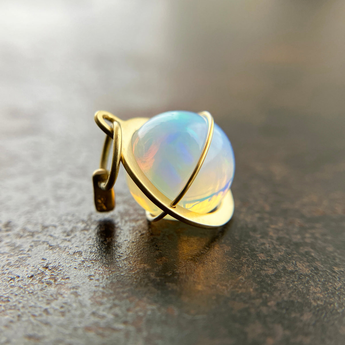 An ethiopian opal orb pendant in an 18k gold setting