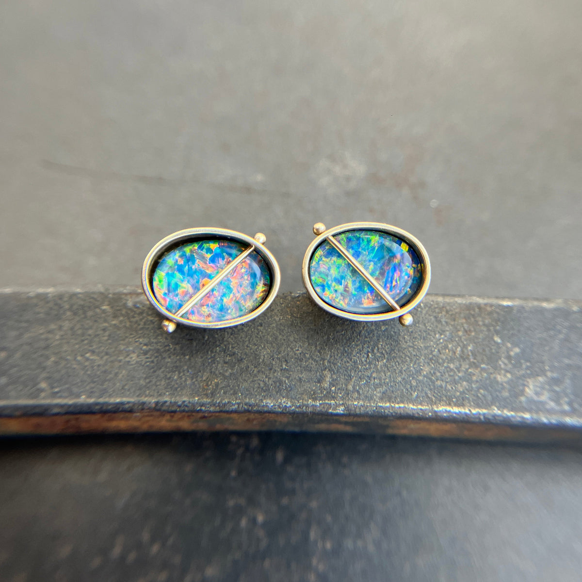 Pair of opal stud earrings on a dark surface