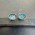 Pair of opal stud earrings on a dark surface
