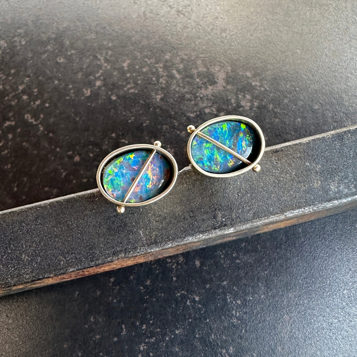 Pair of opal stud earrings on a dark surface