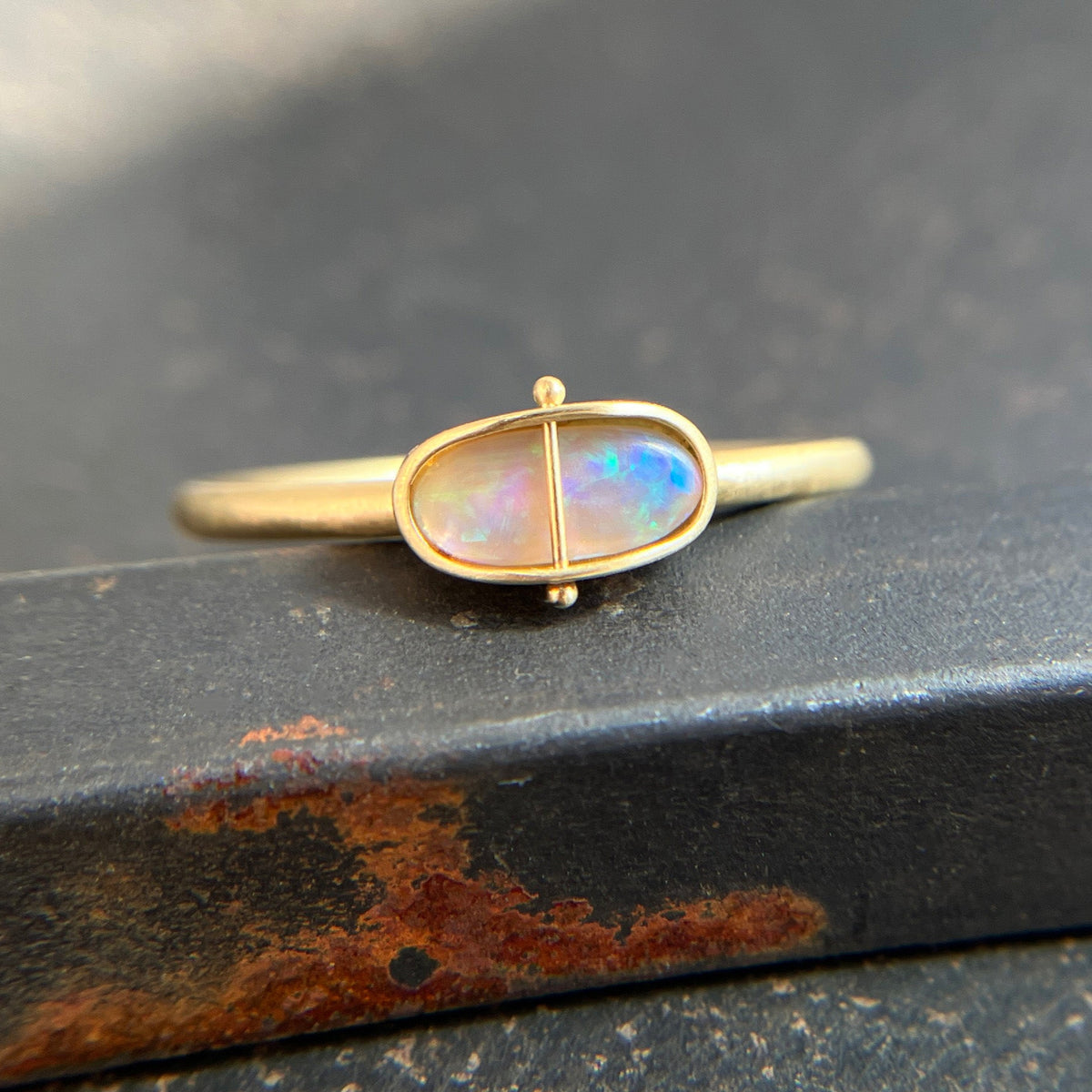 Gold ring with an opal gemstone on a dark surface