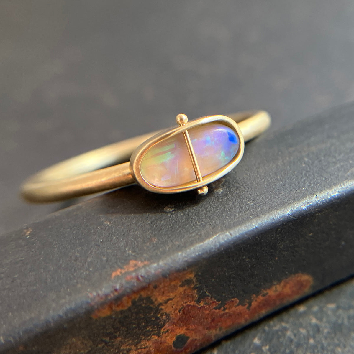 Gold ring with an opal gemstone on a dark surface