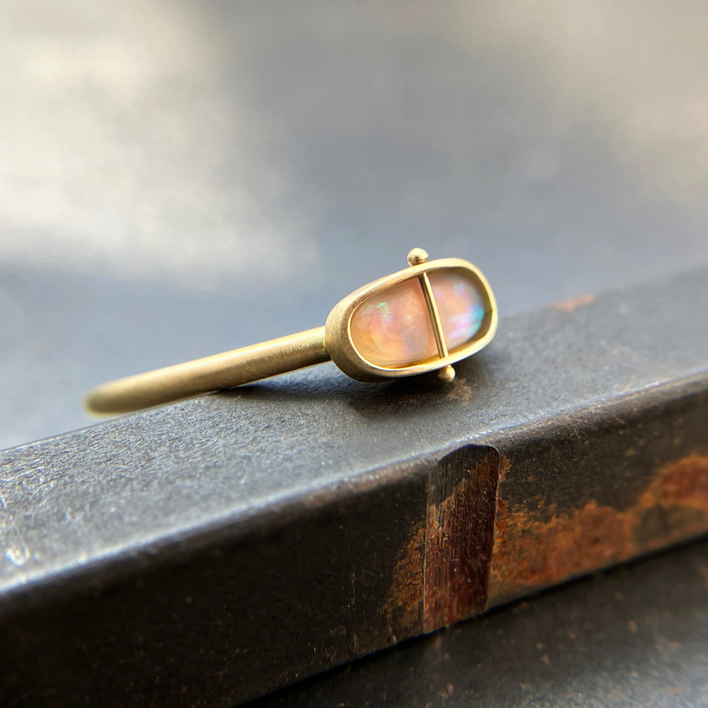 Gold ring with an opal gemstone on a dark surface