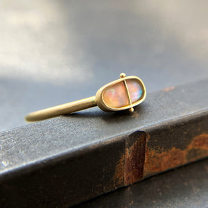 Gold ring with an opal gemstone on a dark surface