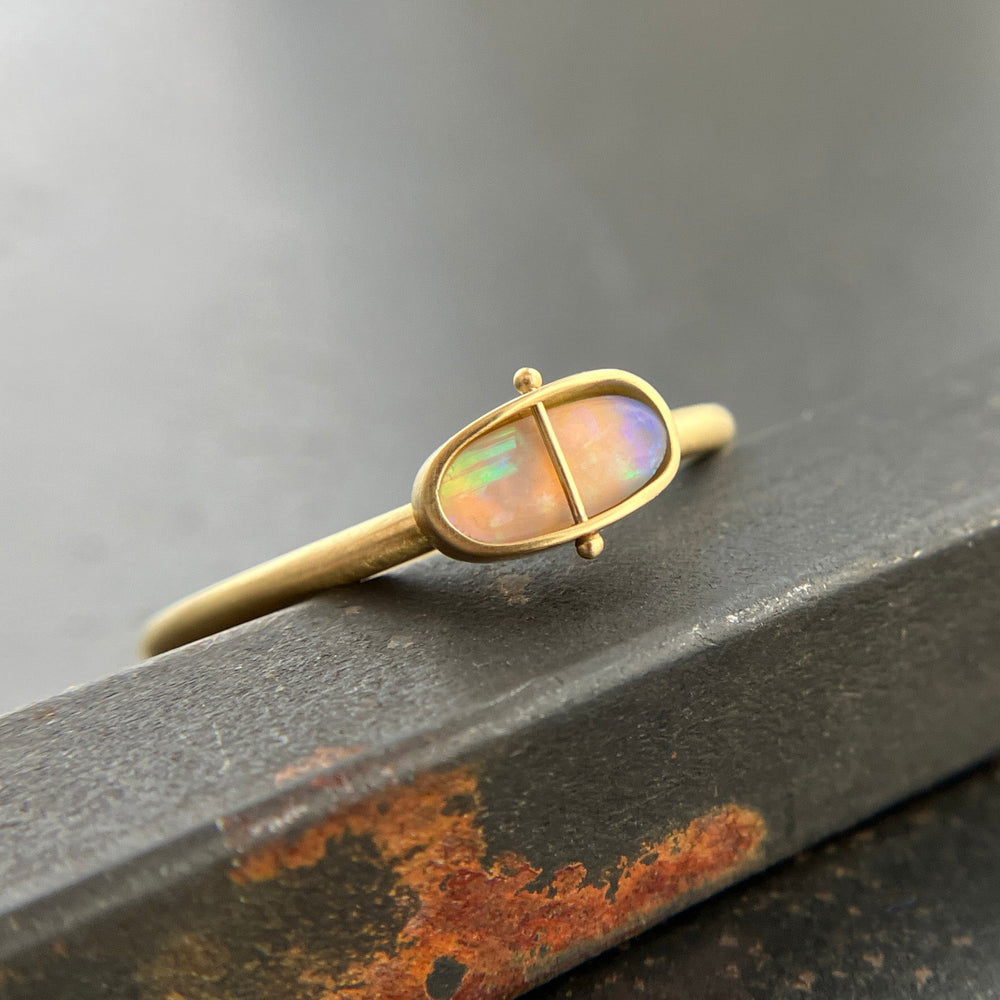 Gold ring with an opal gemstone on a dark surface