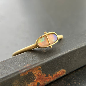 Gold ring with an opal gemstone on a dark surface