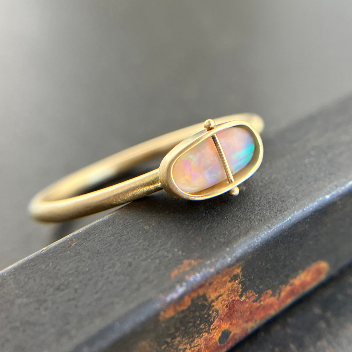Gold ring with an opal gemstone on a dark surface