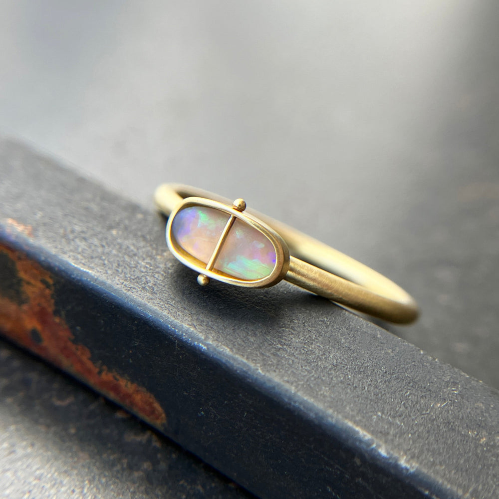 Gold ring with an opal gemstone on a dark surface