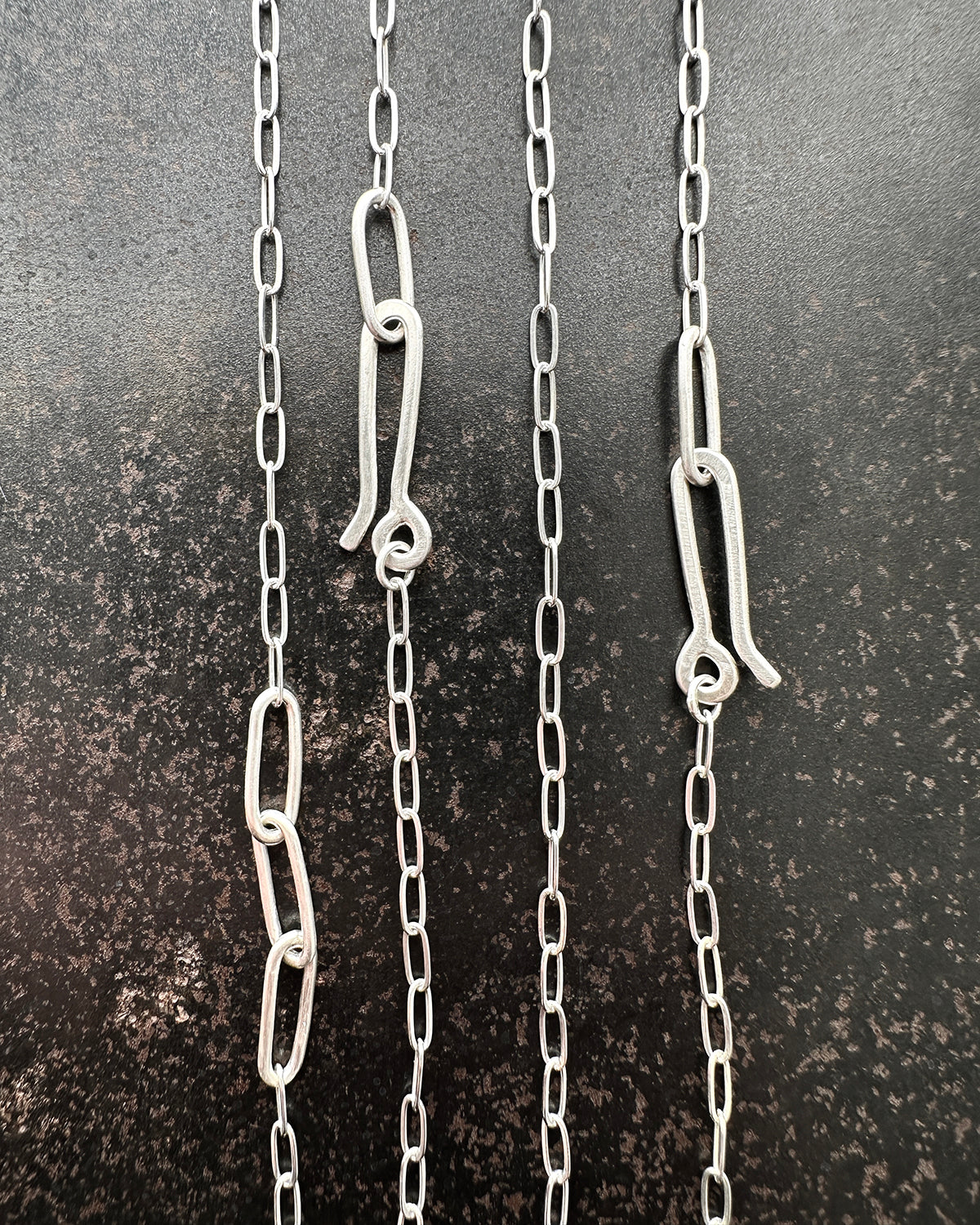 silver paperclip chains with clasp on a dark textured background