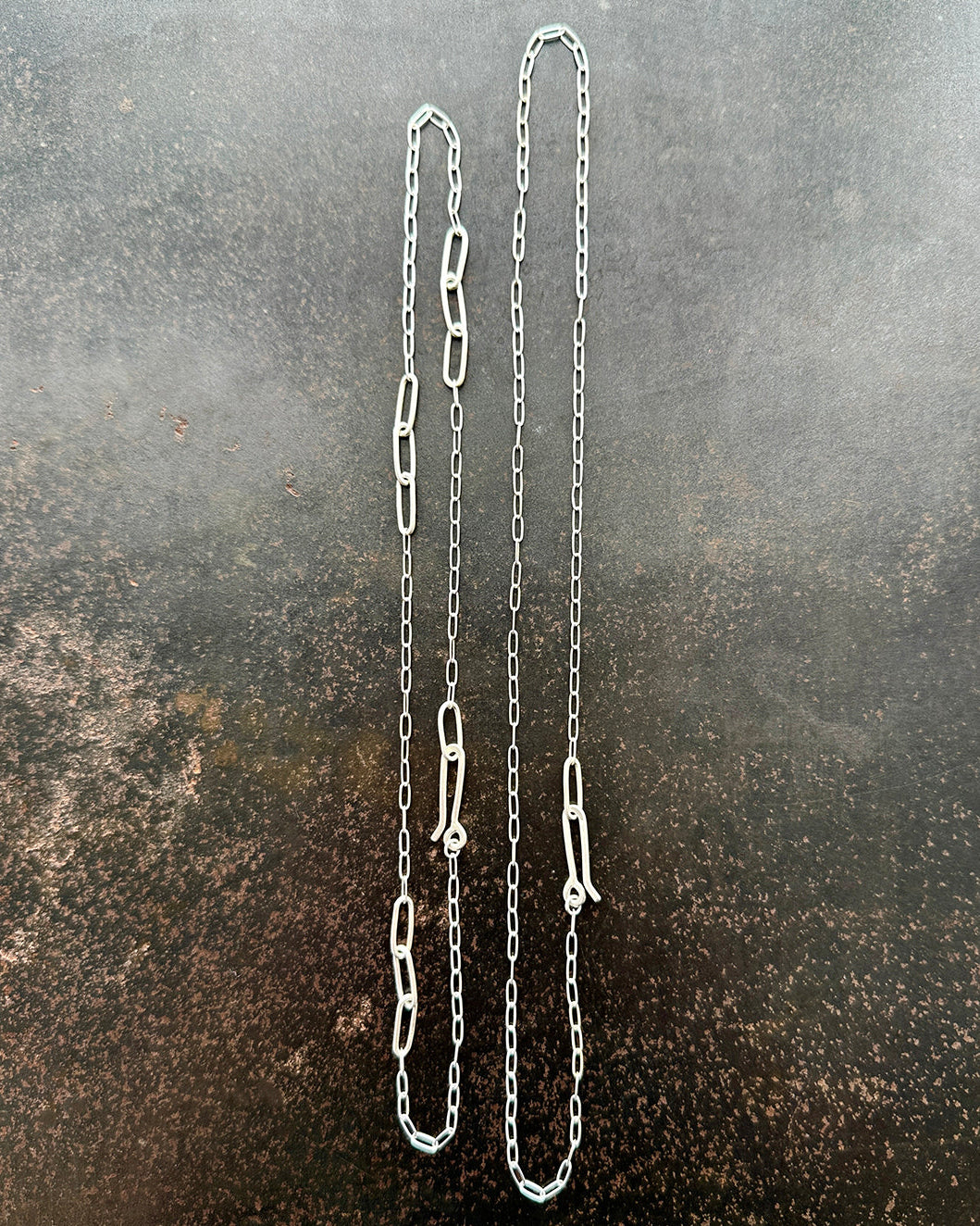 silver paperclip chains with clasp on a dark textured background