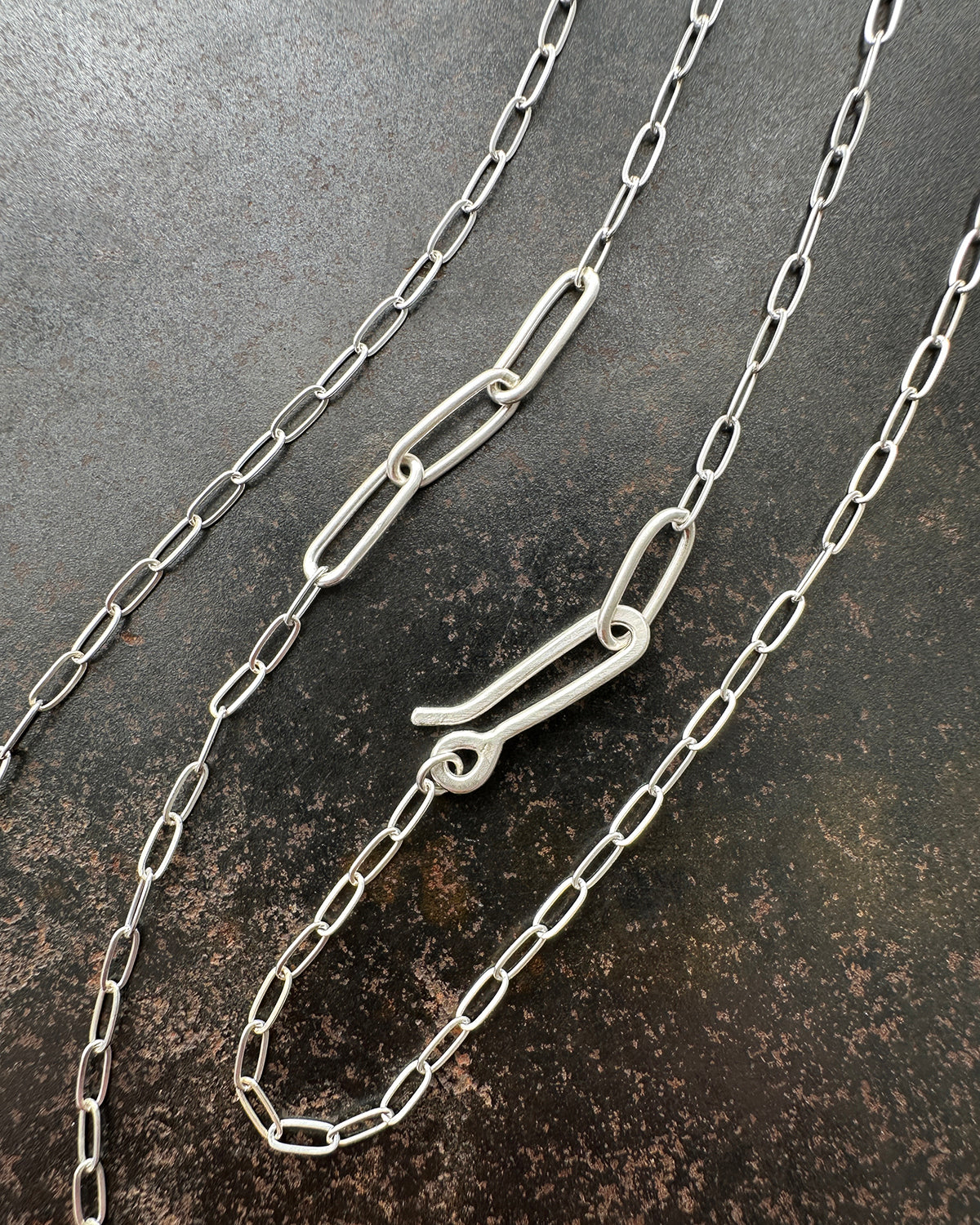 silver paperclip chains with clasp on a dark textured background
