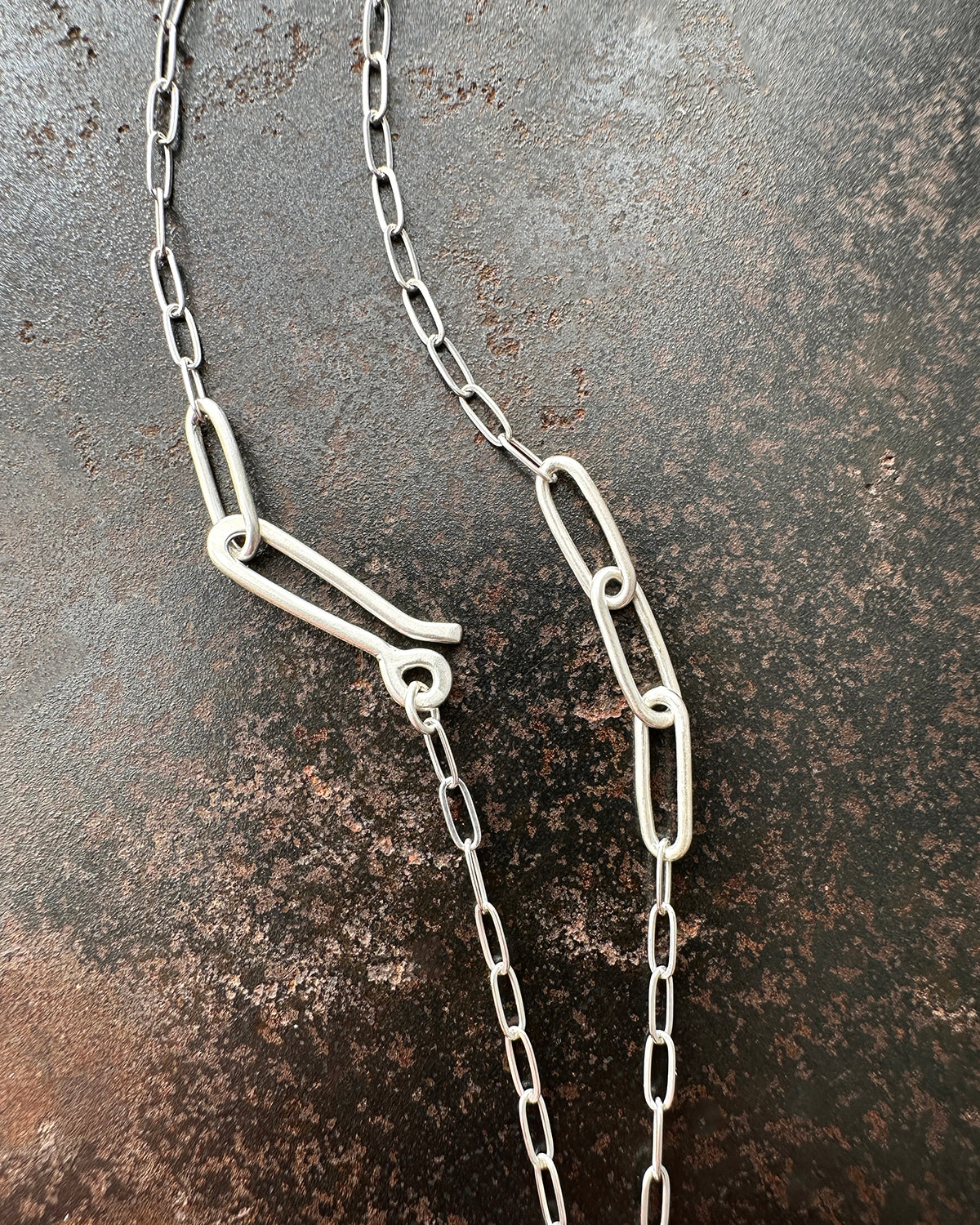 silver paperclip chains with clasp on a dark textured background