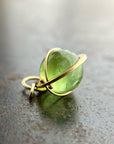 An 18k gold orb pendant with a green peridot sphere gemstone.