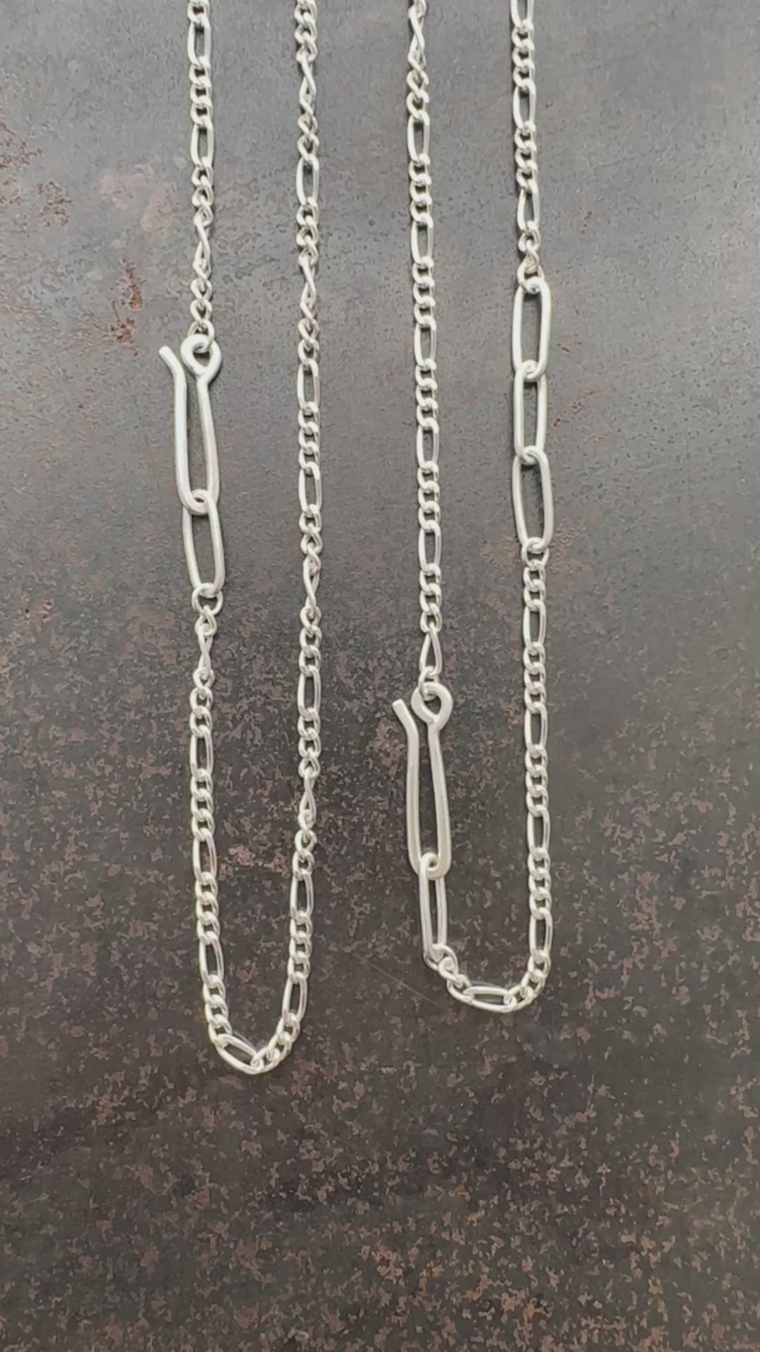 Silver  figaro chain necklace on a textured dark surface
