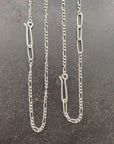Silver  figaro chain necklace on a textured dark surface