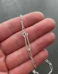Silver  figaro chain necklace on a textured dark surface