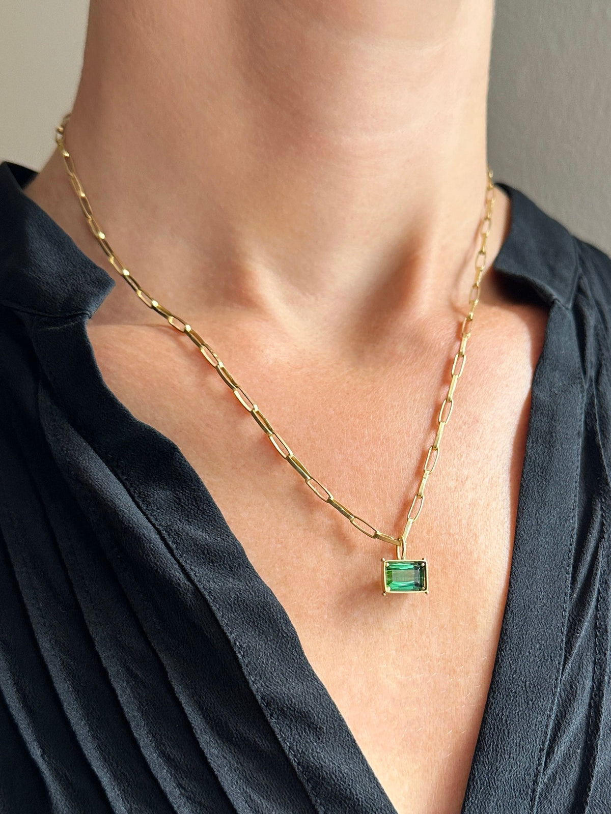green radiant cut tourmaline pendant in 18k gold on a model