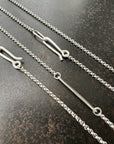 Silver rolo chain necklace on a dark textured surface