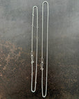 Silver rolo chain necklace on a dark textured surface