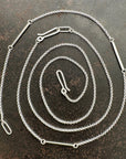 Silver rolo chain necklace on a dark textured surface
