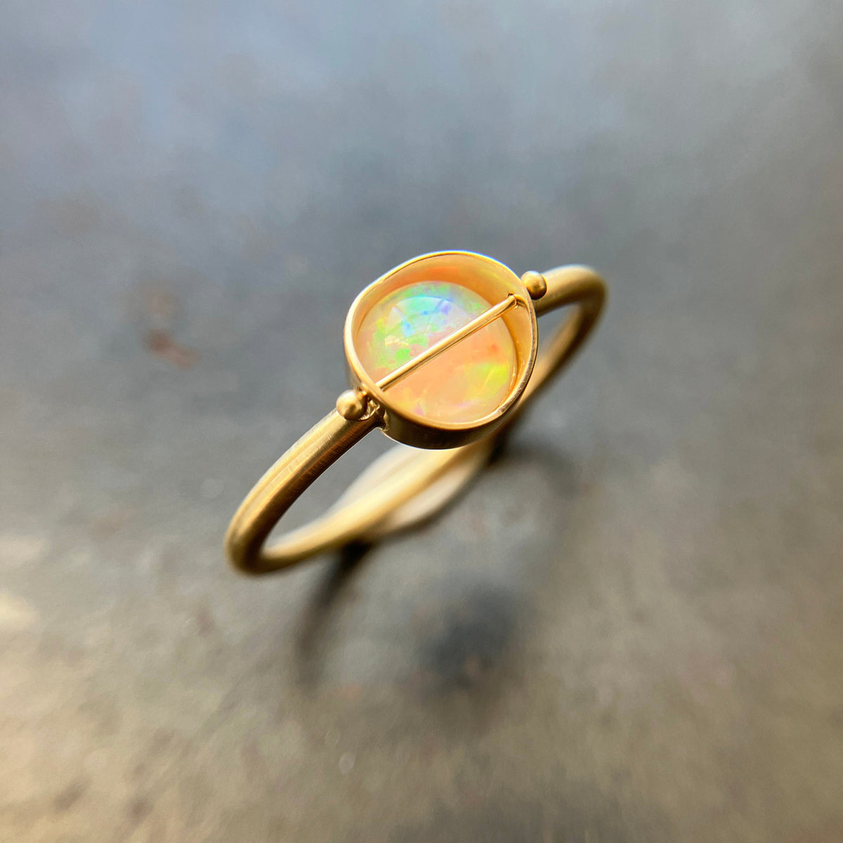 Gold ring with a opal gemstone on a metallic surface