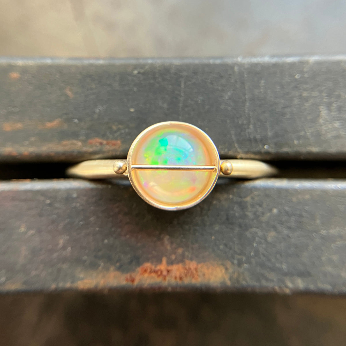 Gold ring with an opal stone on a wooden surface
