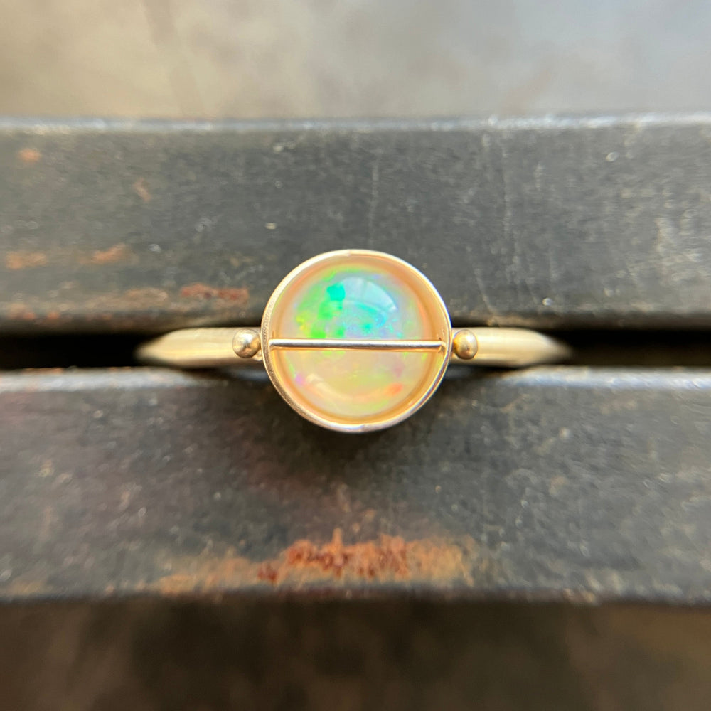 Gold ring with an opal stone on a wooden surface