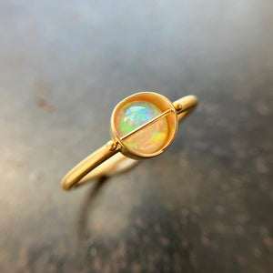 Gold ring with a opal stone on a textured surface