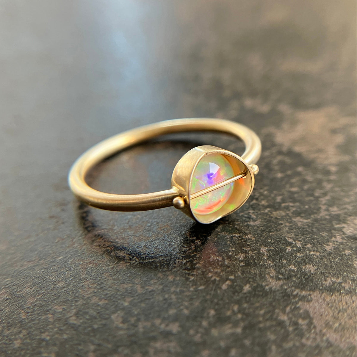 Gold ring with an opal stone on a dark surface