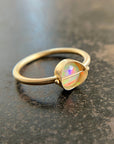 Gold ring with an opal stone on a dark surface