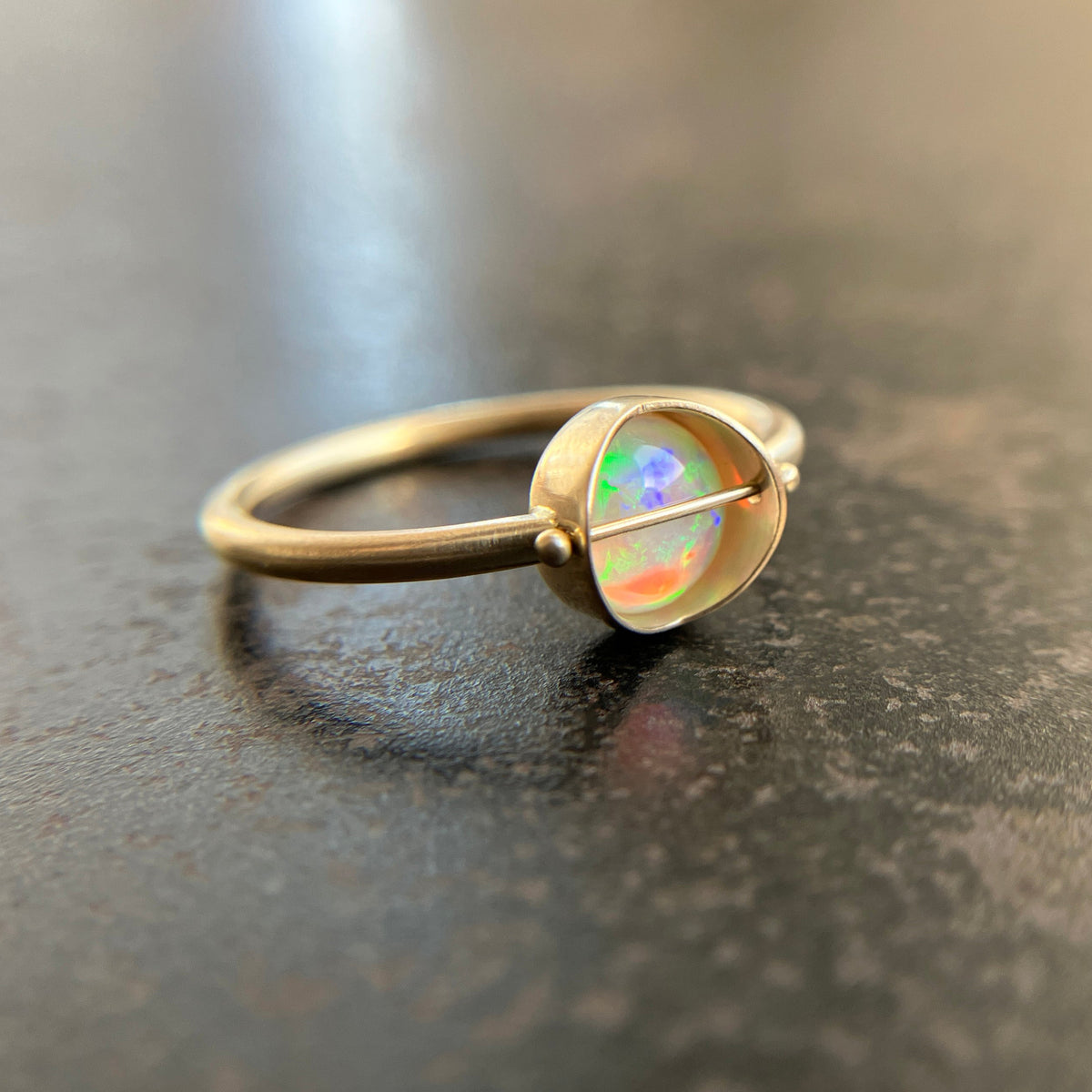 Gold ring with an opal gemstone on a dark surface