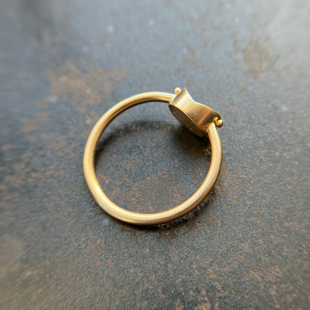 Gold ring with a unique design on a textured surface
