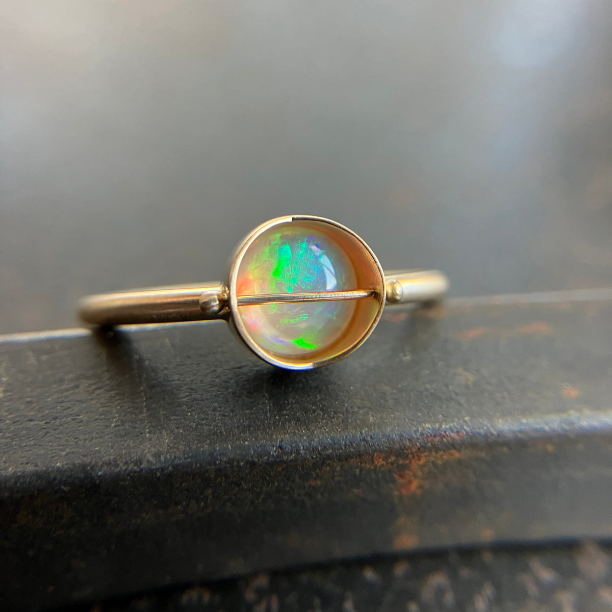 Gold ring with an opal stone on a dark surface
