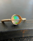 Gold ring with an opal stone on a dark surface