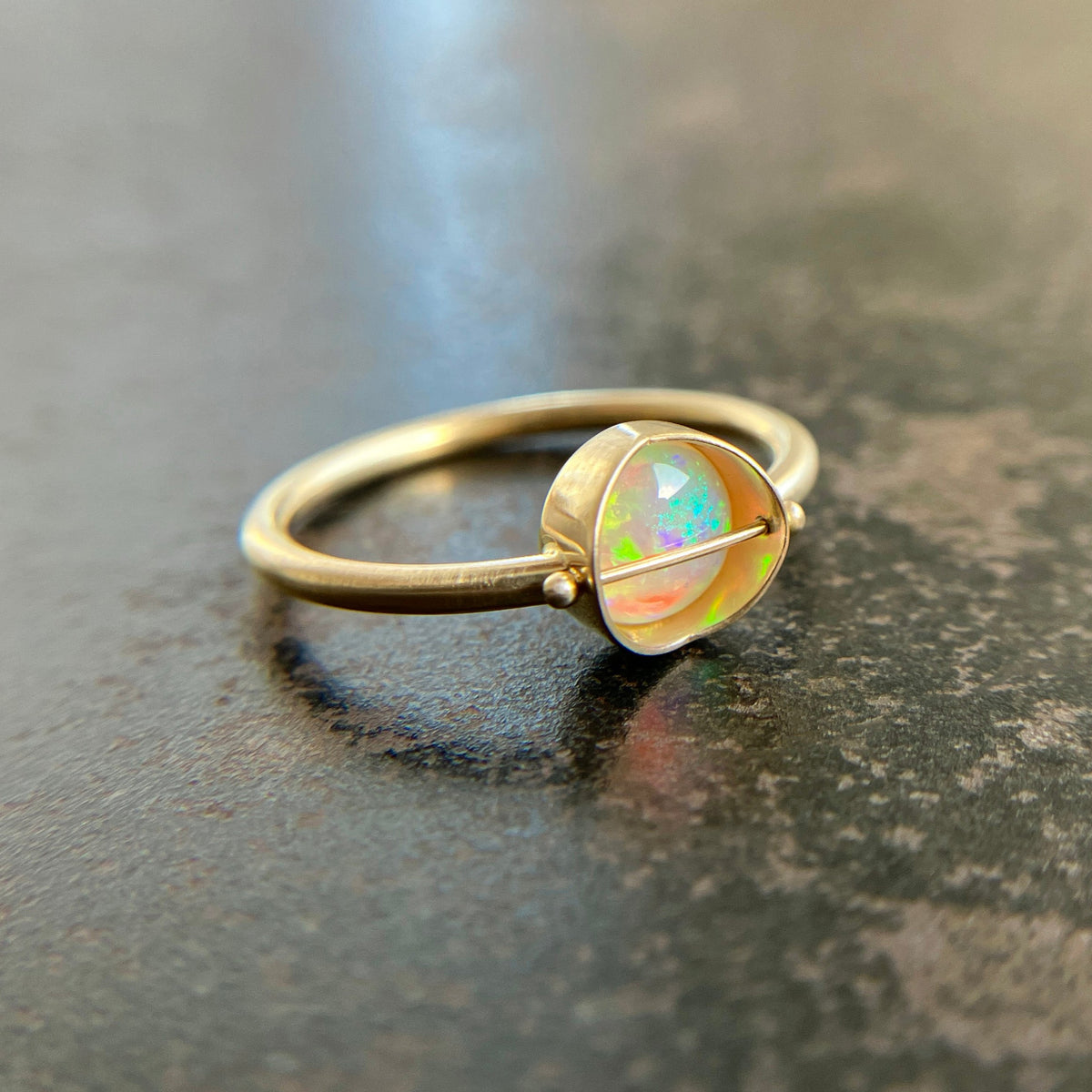 Gold ring with an opal gemstone on a dark surface
