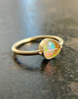 Gold ring with an opal gemstone on a dark surface