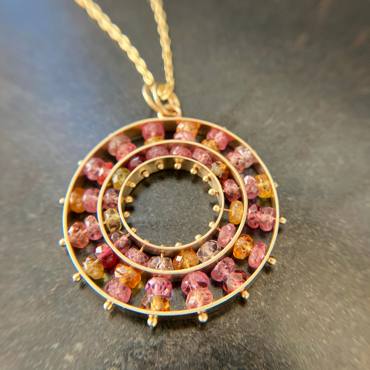 sapphire bead pendant with concentric circles of 14k gold